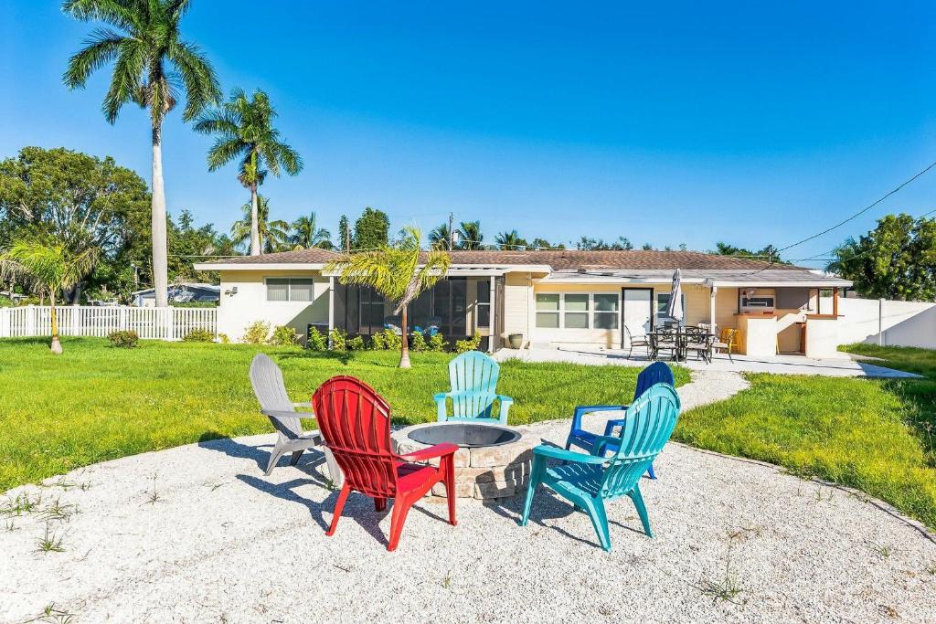 four chairs and a table in front of a house at Riverside Retreat: Deck Bar, FirePit, Boat Parking in Fort Myers