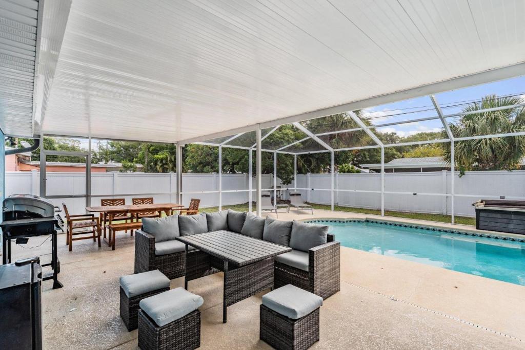 a patio with a table and chairs next to a pool at Ocean Blue Heated Pool Home in Largo