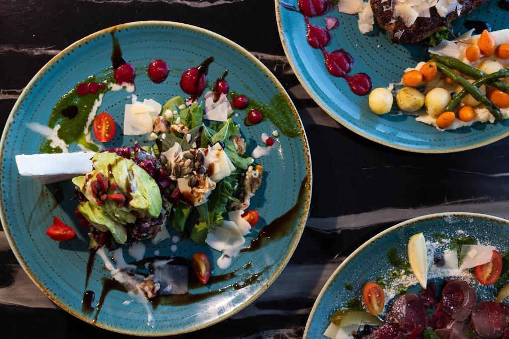 three blue plates of food on a table at Leonardo Crystal Cove Hotel & Spa – Adults only in Protaras