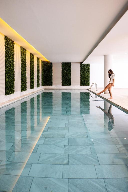 a woman walking along the side of a swimming pool at Leonardo Crystal Cove Hotel & Spa – Adults only in Protaras