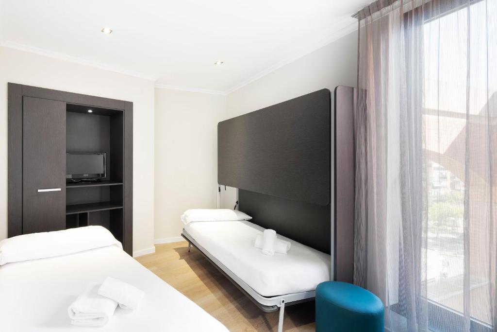 a hotel room with two beds and a flat screen tv at Hotel Alimara in Barcelona
