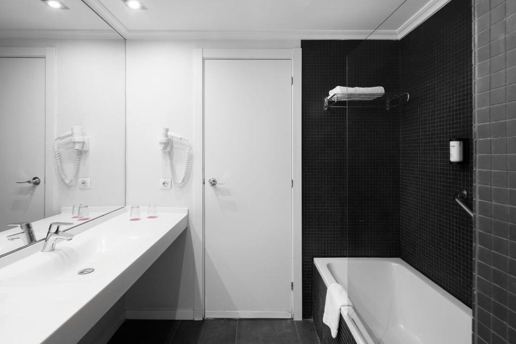 a bathroom with two sinks and a tub and a shower at Hotel Alimara in Barcelona