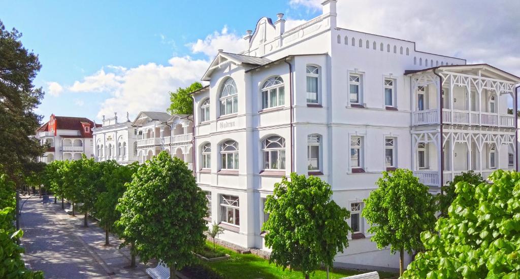 a white building with trees in front of it at Villa Gudrun by Unsere Urlaubszeit in Binz