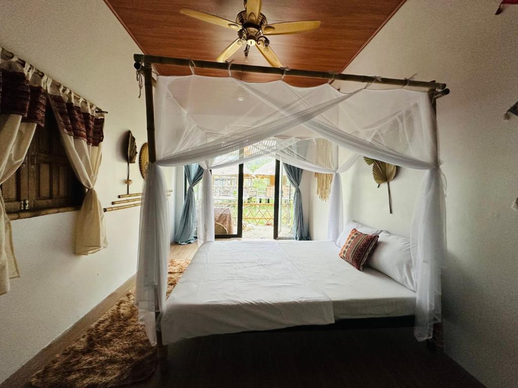 a bedroom with a canopy bed with a ceiling fan at Wild Orchid Relaxing Bungalow in Làng Cac