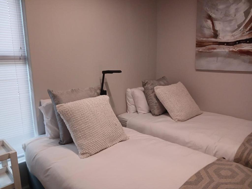 two beds with pillows on them in a room at 106 Mossel Cove in Mossel Bay