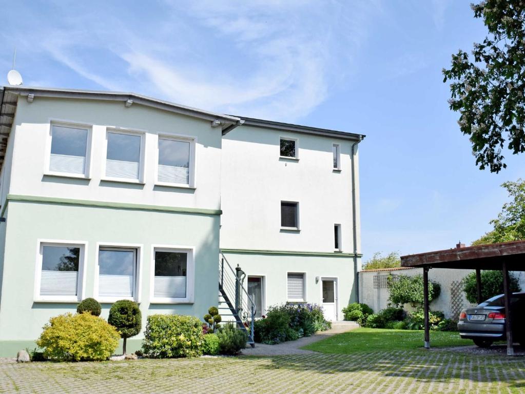a white house with a car parked in the driveway at Ferienwohnung Gartenblick in Altefähr