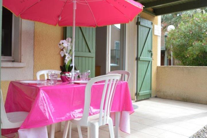 une table rose avec des chaises et un parasol dans l'établissement NP045-018 Appartement 2 pièces, Narbonne Plage, à Narbonne-Plage