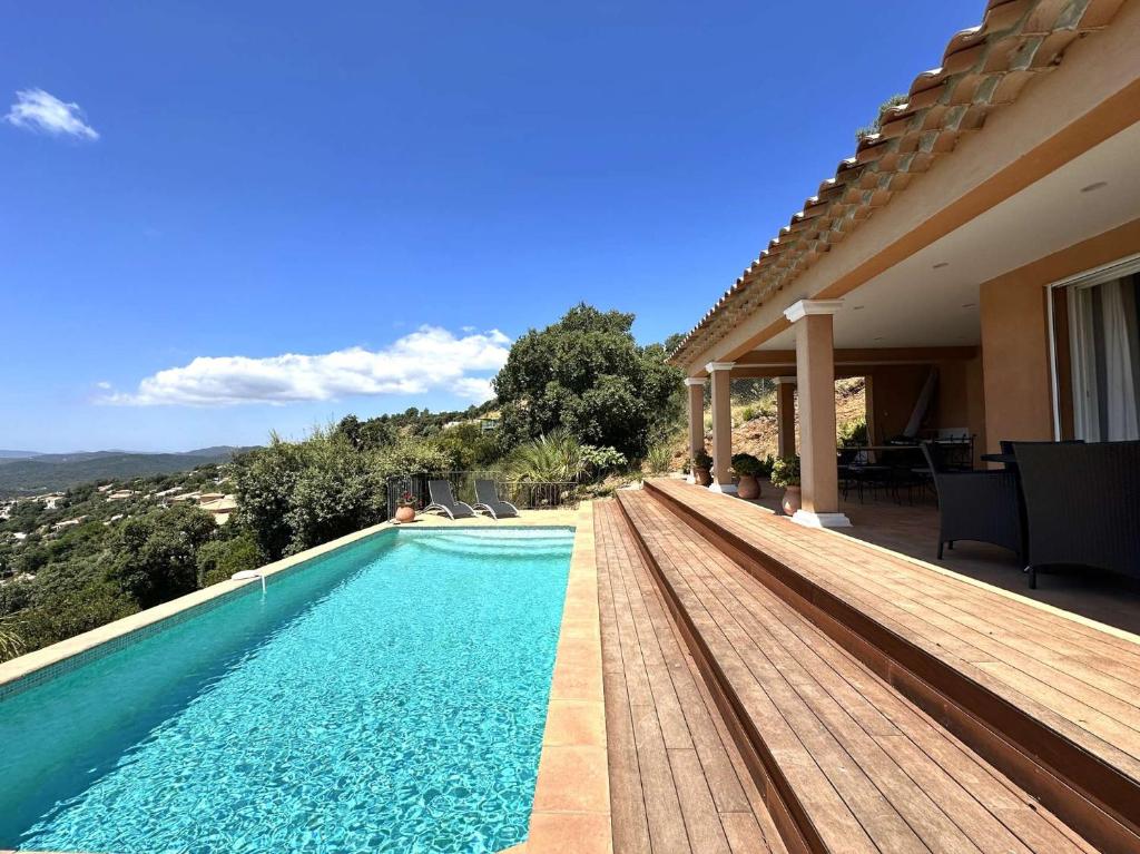 une piscine avec une terrasse en bois à côté d'une maison dans l'établissement Villa Blue Hill pour 6 personnes avec piscine privée et vue mer à La Londe-Les-Maures, à La Londe-les-Maures