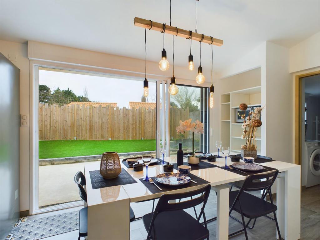 une salle à manger avec une table et des chaises et une grande fenêtre dans l'établissement Les Sables d'Olonne, maison avec jardin pour 6, à Les Sables-dʼOlonne