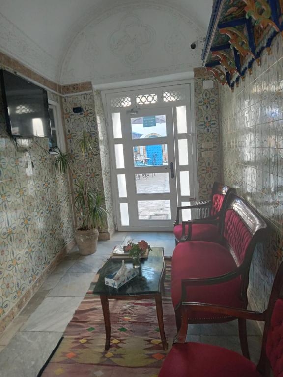 a living room with a red couch and a table at Hôtel Bou Fares in Sidi Bou Saïd