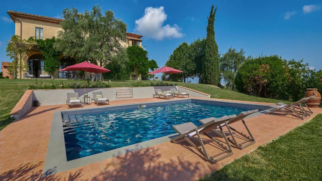 a swimming pool with chairs and umbrellas in front of a house at Villa Marliana in Cerreto Guidi
