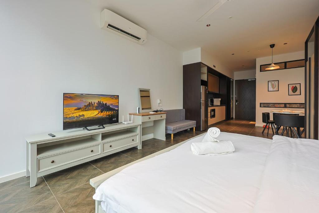 a bedroom with a white bed and a flat screen tv at Borderless Swimming Pool - Invincible Twin Towers View - Free WiFi in Kampong Gombak Utara