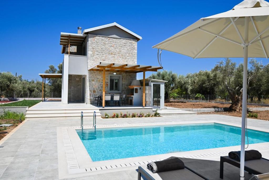 a swimming pool with an umbrella and a house at Villa Penelope Halipoma in Lefkada Town