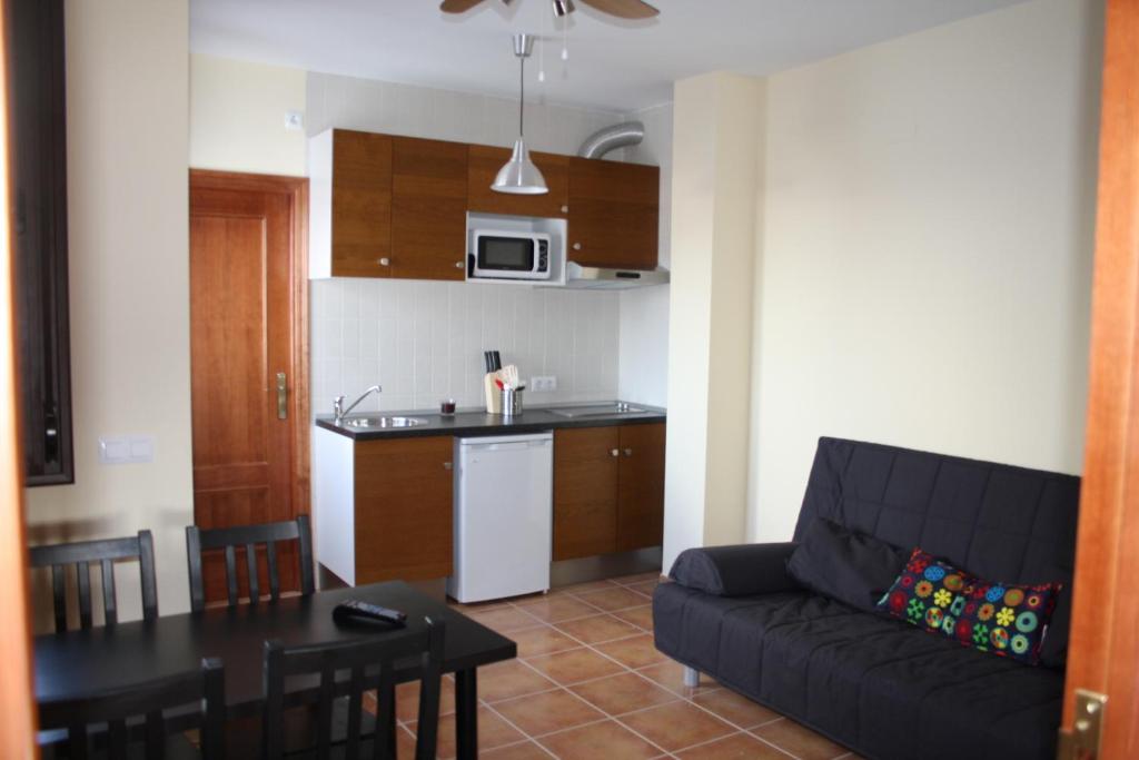カサジャ・デ・ラ・シエラにあるApartamentos Turisticos Rurales El Puaのリビングルーム(ソファ、テーブル付)、キッチンが備わります。