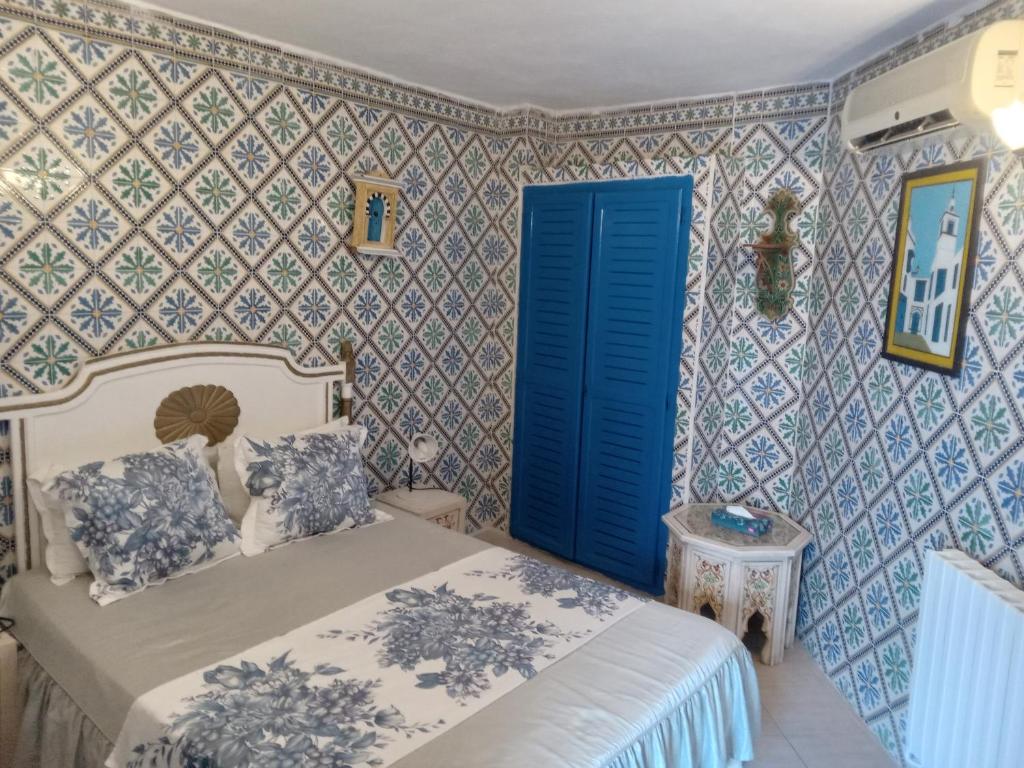 a bedroom with a bed and a blue door at Hôtel Bou Fares in Sidi Bou Saïd