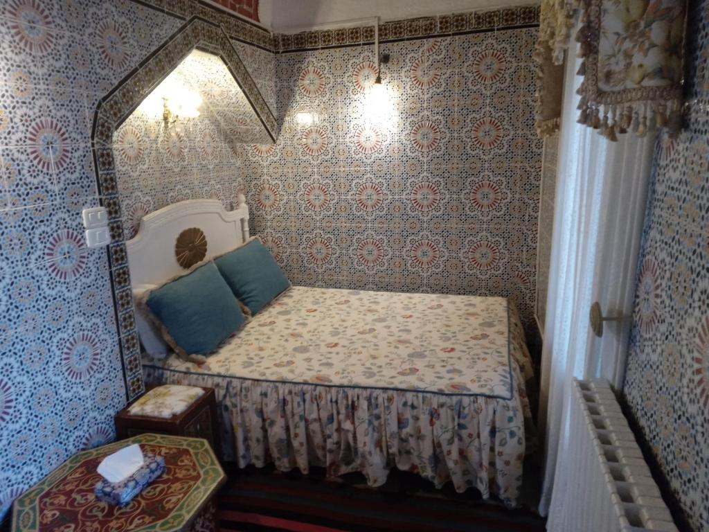a small bedroom with a bed in a room with wallpaper at Hôtel Bou Fares in Sidi Bou Saïd