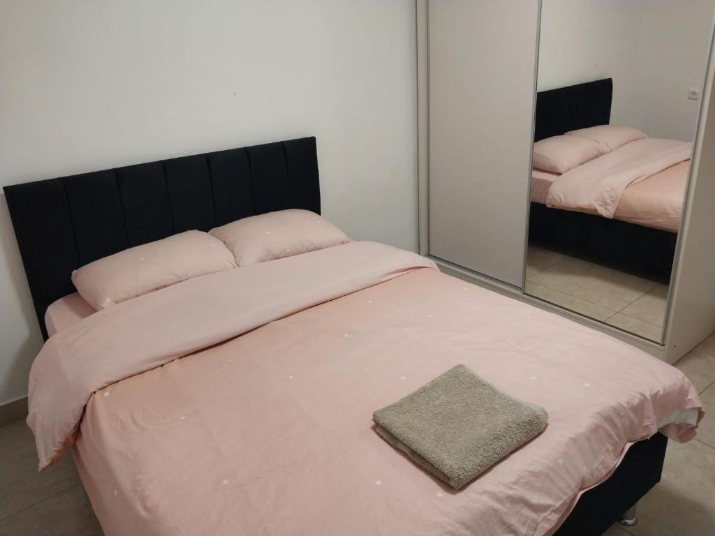 a bedroom with a bed with pink sheets and a mirror at דירה משפחתית מרווחת in Ashkelon
