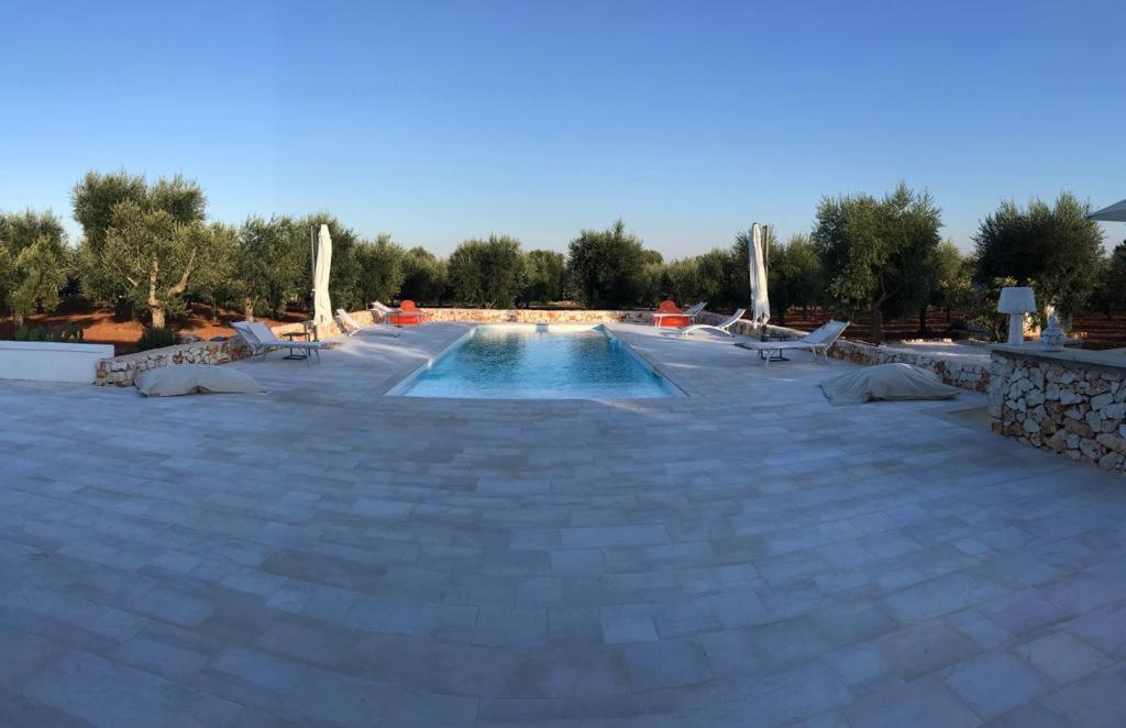 une piscine avec des chaises longues et une visière de piscine dans l'établissement La Corte Bianca, à Ostuni