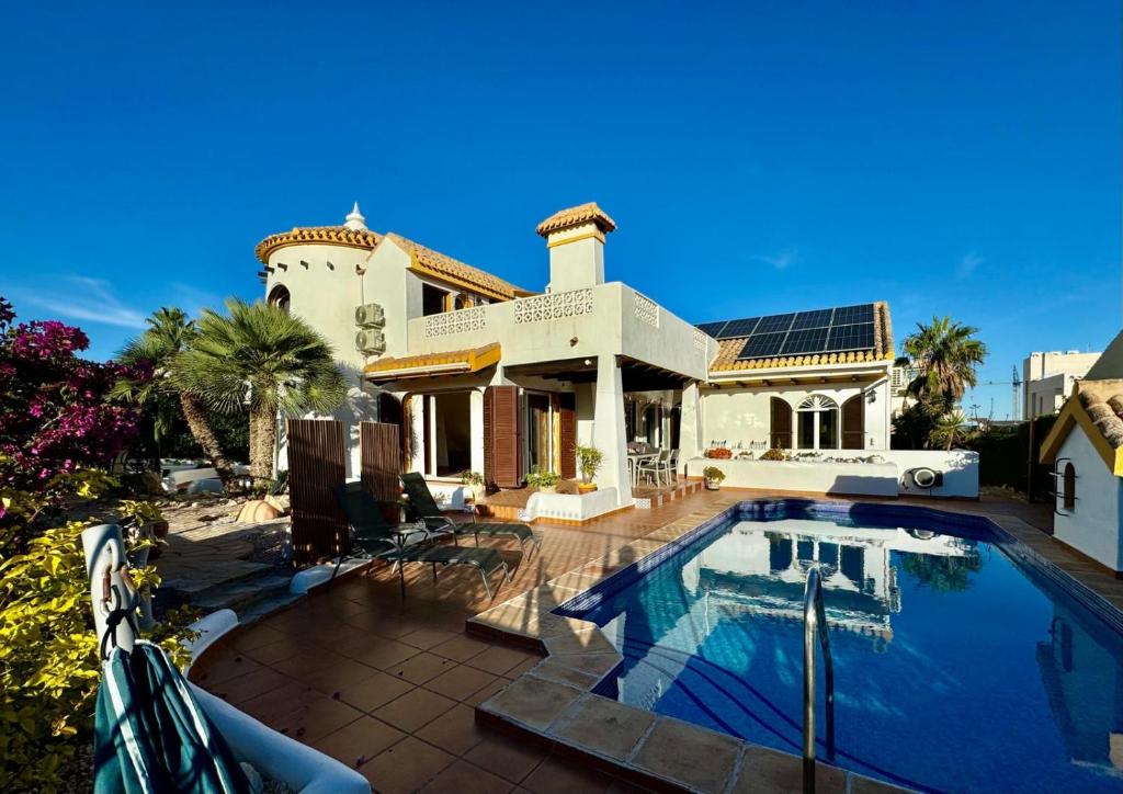a house with a swimming pool in front of it at Ibiza style villa first line to golf! in Villamartin