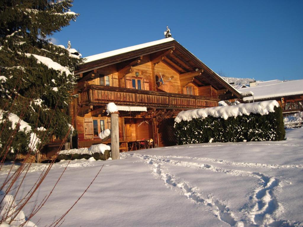 a log cabin in the snow with footprints in the driveway at Ferienhaus Höllwart in Pfarrwerfen