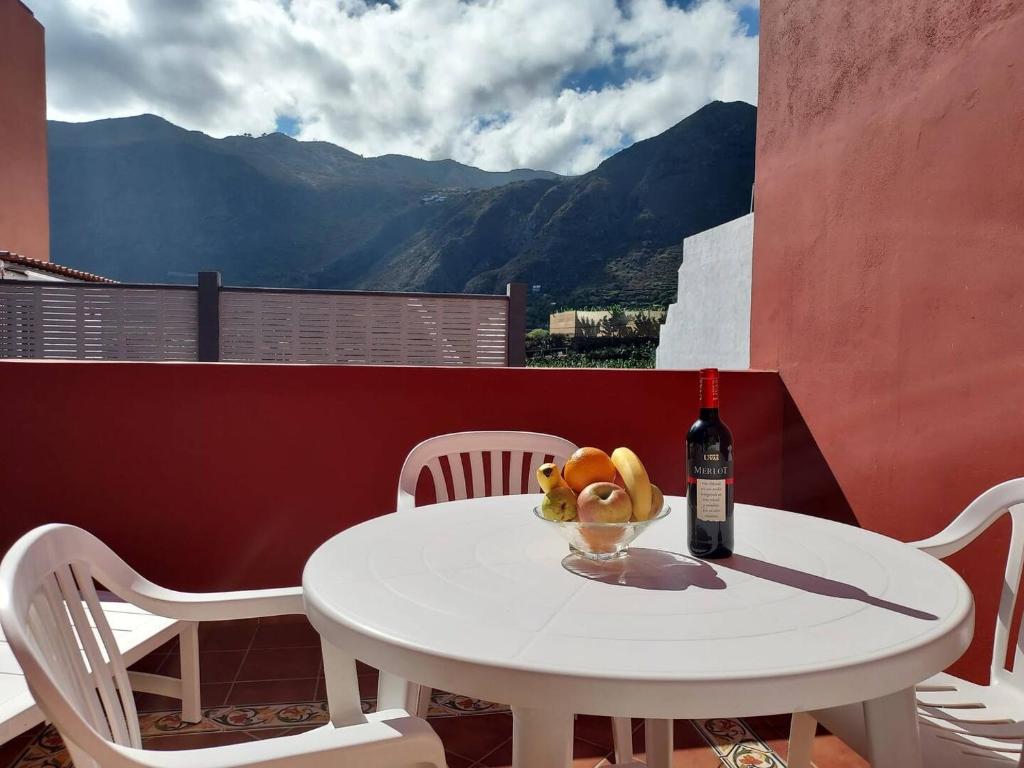 a table with a bottle of wine and a bowl of fruit at CHC - Apartamento Los Silos Tulipanes 2 in Los Silos