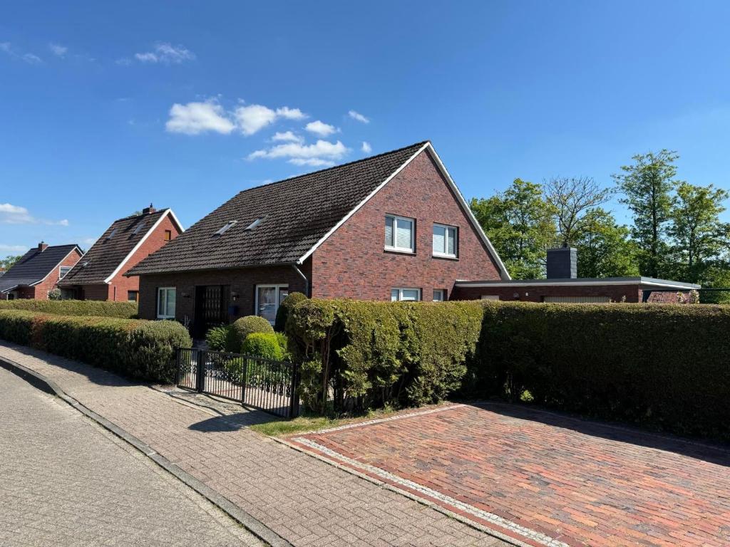 una casa de ladrillo con un seto delante de una entrada en Ferienhaus Janßen, en Esens