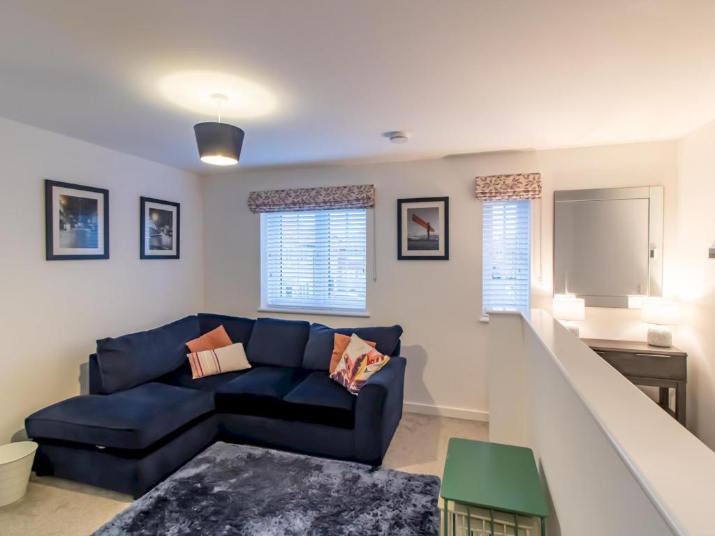 a living room with a blue couch and a staircase at Pass the Keys Charming Coastal Retreat – 1-Bedroom Flat in Blyth in Blythe