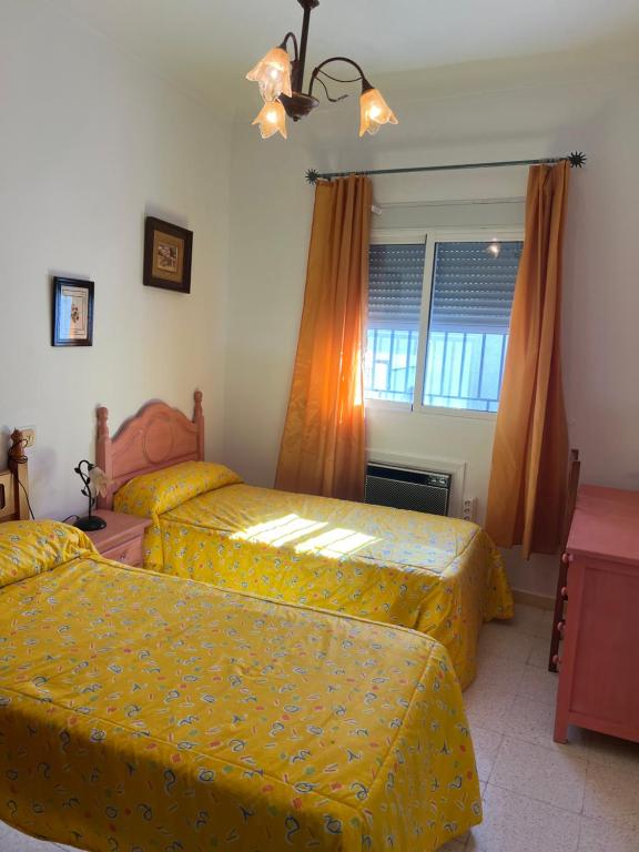 a bedroom with two beds with yellow covers and a window at Casa familiar pueblo in Valencina de la Concepción