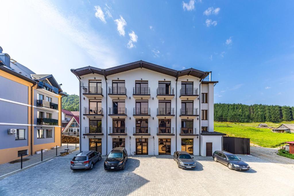 a large white building with cars parked in a parking lot at Garda - Breakfast included in the price Restaurant Free Parking Mountain view Kitchen in the apartment separate entrance in Bukovel