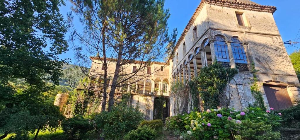 un vieux bâtiment en pierre avec des fleurs devant lui dans l'établissement Maison au cœur des Cévennes, à Molières-Cavaillac