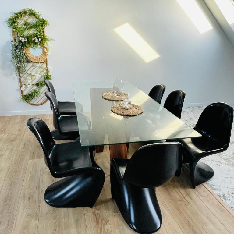 une salle à manger avec une table en verre et des chaises noires dans l'établissement Élégant T4 lumineux en centre-ville, à Lorient