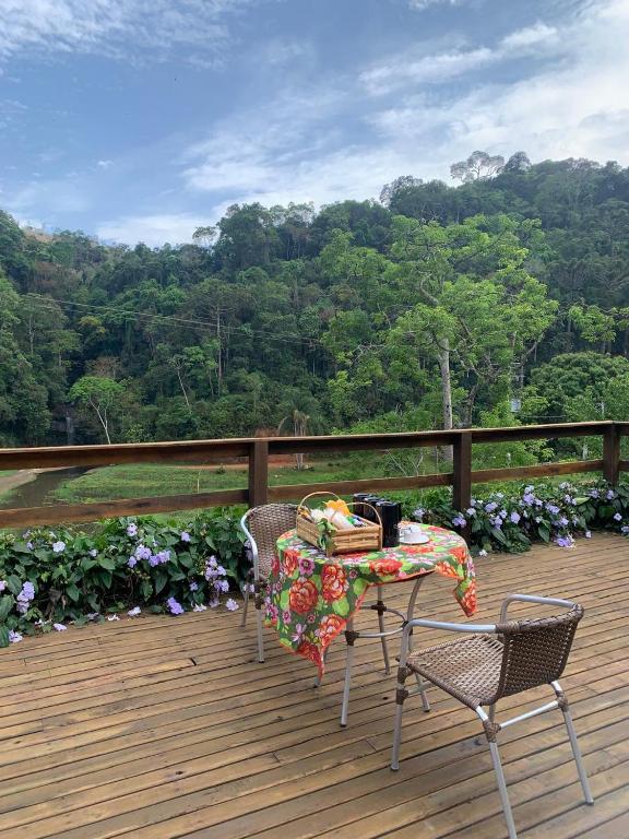 a table and chairs on a wooden deck with a view at Pousada Shangri-lá in Cunha