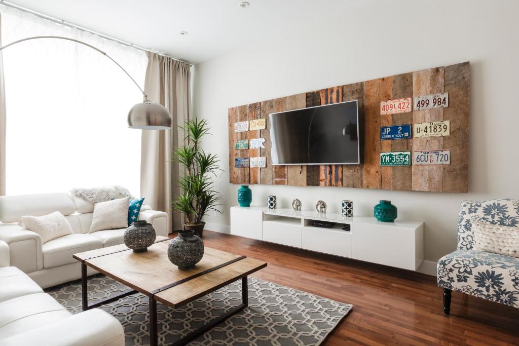 a living room with a couch and a tv on a wall at MTLVacationRentals - The FabFour in Montréal