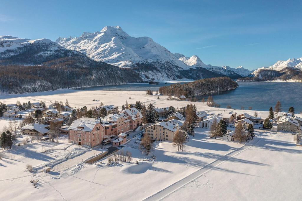 an aerial view of a town with snow covered mountains at Parkhotel Margna Superior in Sils Maria
