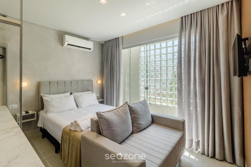 a bedroom with a bed and a couch and a window at Lindo Estúdio Funcional em Goiânia SLV0011 in Goiânia