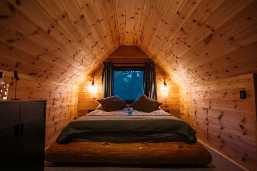 a bed in a wooden room with a window at Szürke Szarvas in Szuha