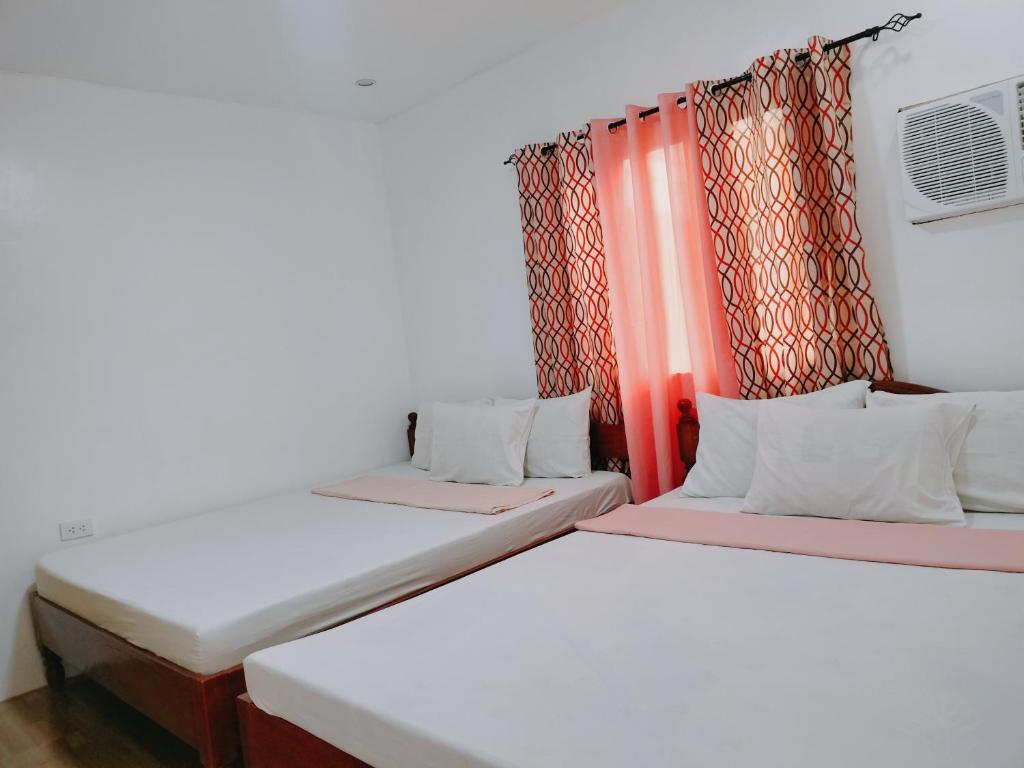 two beds in a room with red curtains at Family Suite 4-6 Pax GLENMARK'S Homestay near the beach in Pagudpud