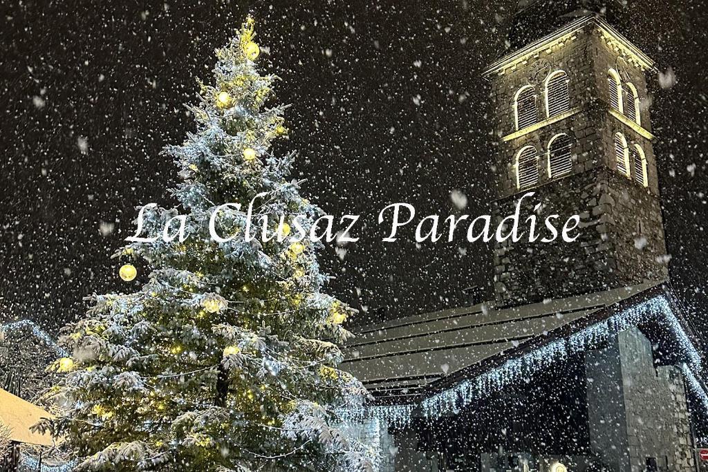 a christmas tree in front of a building in the snow at Duplex skis aux pieds centre village - 6 couchages - 2 salles de bain in La Clusaz