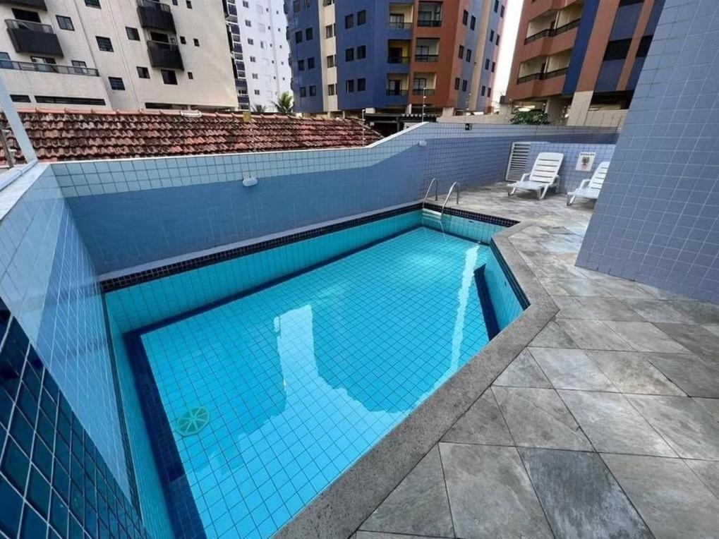 Una gran piscina azul en un edificio. en Apto Pé na Areia com Vista Mar, Churrasqueira e Espaço para 8 Pessoas, en Praia Grande