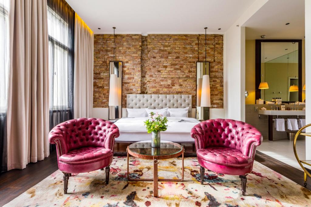 een slaapkamer met een bed en twee roze stoelen bij Hotel Zoo Berlin in Berlijn