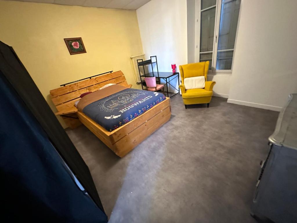 - une chambre avec un lit en bois et une chaise jaune dans l'établissement Studio Gare SNCF, à Tarbes