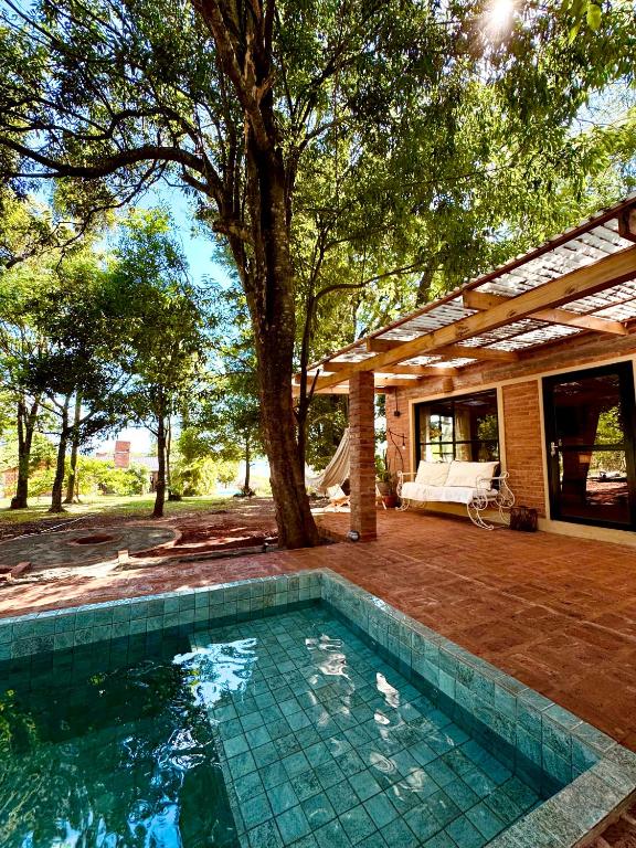 a swimming pool in front of a house with a tree at Casa Bambú - Brisas del Lago in Puerto Bossetti