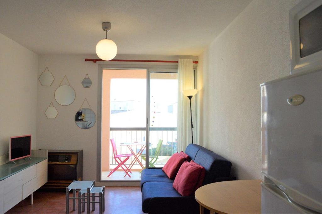 a living room with a blue couch and a table at Studio CAP D'AGDE CT121-019 in Cap d'Agde