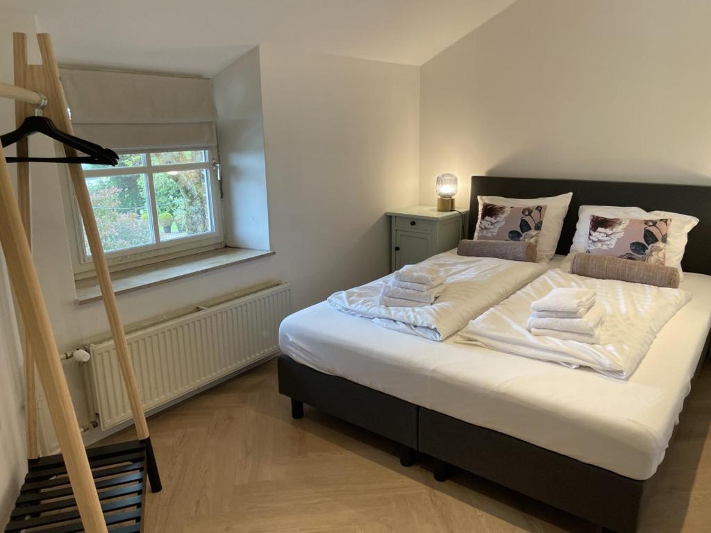 a bedroom with a bed with white sheets and pillows at Sfeervolle 4 persoons cottage vlakbij Valkenburg in Voerendaal