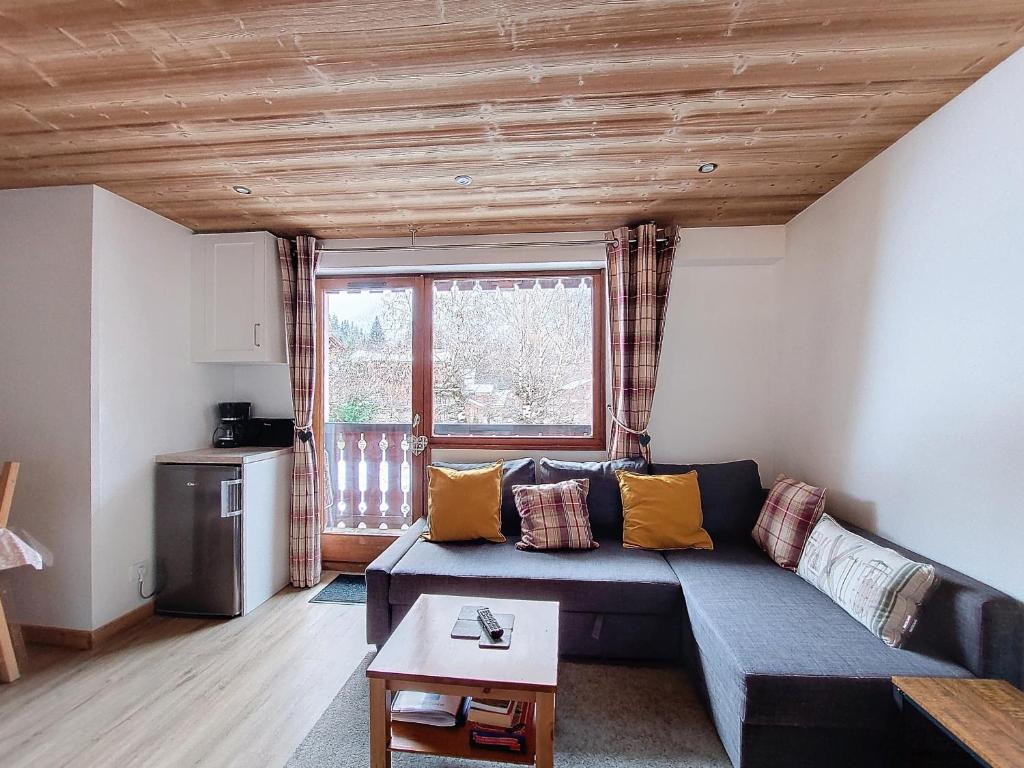 un salon avec un canapé et une fenêtre dans l'établissement APPARTEMENT 6 COUCHAGES - ST JEAN D'AULPS - PROCHE PIED DES PISTES - PROCHE MORZINE - Cimes 44, à Saint-Jean-dʼAulps