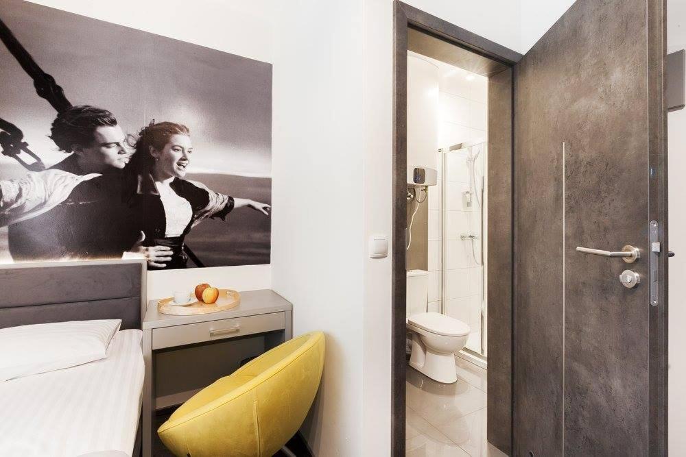 a bedroom with a bathroom with a poster on the wall at Pokoje Cinema in Poznań