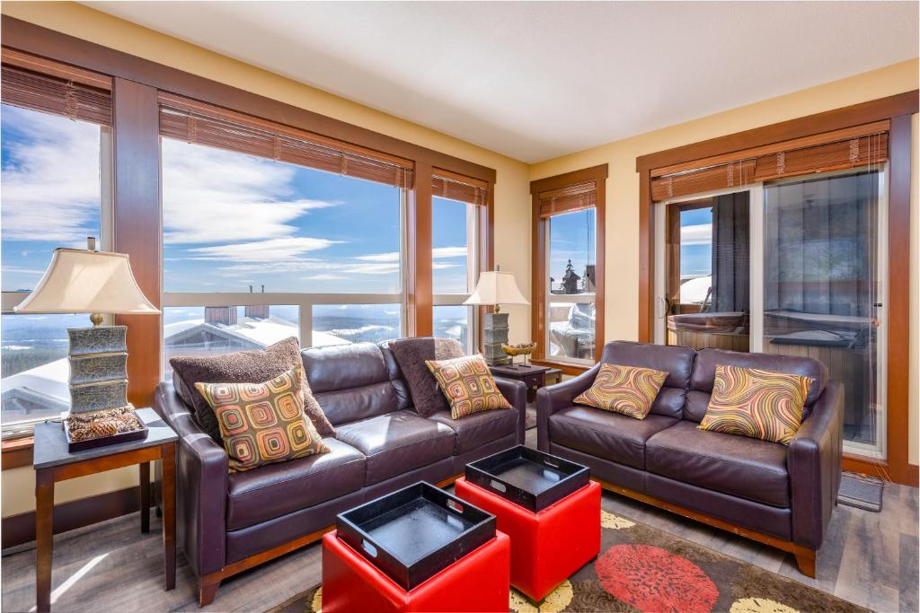 ein Wohnzimmer mit Ledersofa und großen Fenstern in der Unterkunft Stonegate Resort Unit C105 in Kelowna