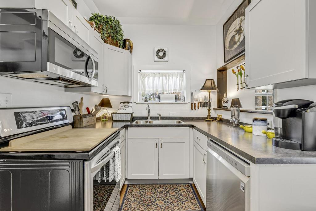 une cuisine avec des armoires blanches et des appareils en acier inoxydable dans l'établissement Tyson House Historic Downtown Cottage, à Cedar Key