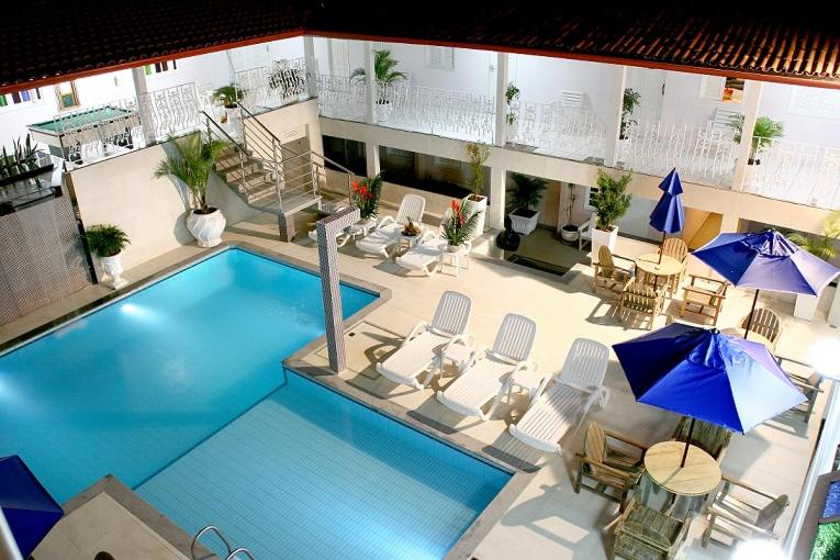 an overhead view of a swimming pool with chairs and umbrellas at Ancoradouro Hotel - Centro De Porto Seguro in Porto Seguro
