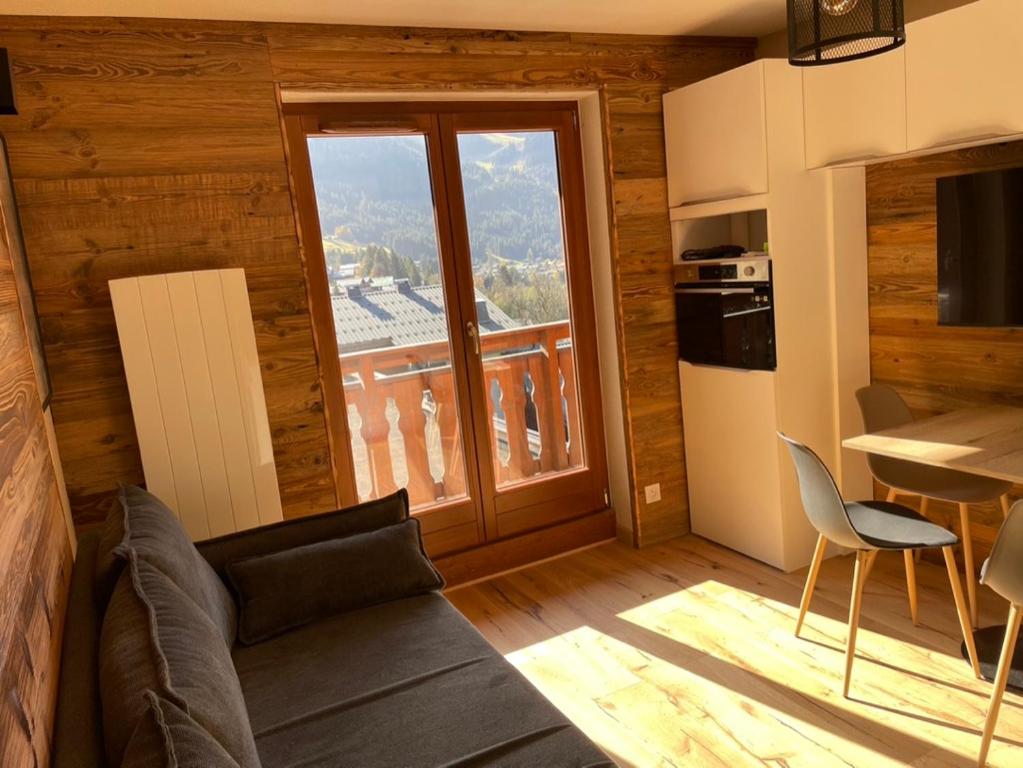 un salon avec un canapé et une grande fenêtre dans l'établissement Charmant Studio proche du centre de Châtel, à Châtel